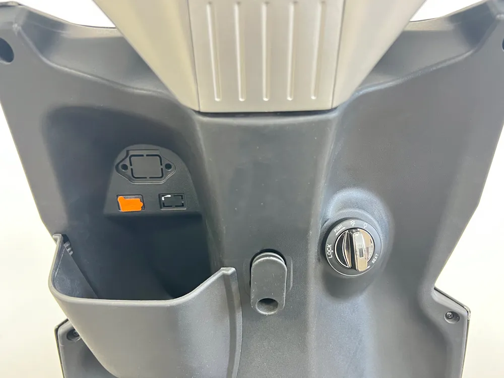 Close-up of electric scooter ignition switch and utility hook on inner front panel